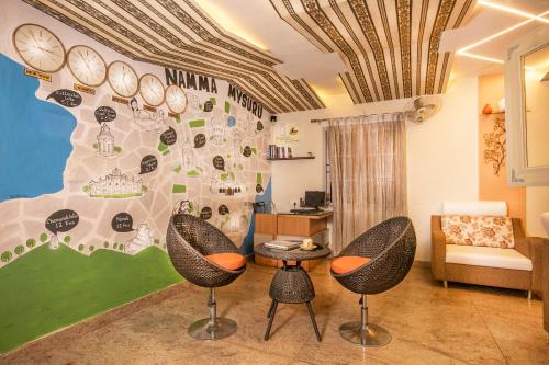 Una sala de estar con dos sillas y una pared con relojes. en Aishwarya Residency, en Mysore