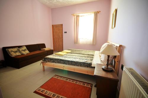 a bedroom with a bed and a couch and a window at Gergely Tanya in Garabonc