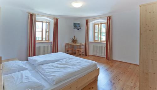 a bedroom with a bed and a table and two windows at Hotel Zur Kirche in Magrè allʼ Adige