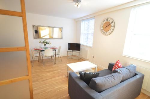 a living room with a couch and a clock on the wall at 3B Soho Studios 3rd floor by Indigo Flats in London