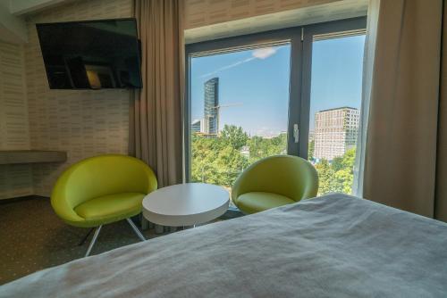 a hotel room with a bed and two chairs and a window at Q Hotel Plus Wrocław in Wrocław