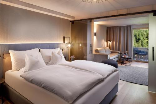 a bedroom with a large bed and a living room at Adler Inn Tyrol Mountain Resort SUPERIOR in Tux