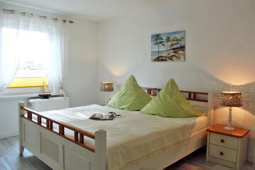 - une chambre avec un grand lit et des oreillers verts dans l'établissement Zur Alten Boddenfischerei Ferienwohnung Zander, à Neuendorf Heide