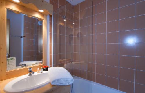 uma casa de banho com um lavatório, um espelho e uma banheira em Résidence Odalys L'Orée des Pistes em Le Dévoluy