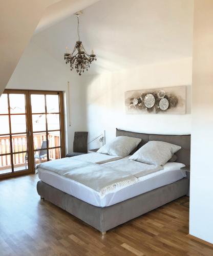 a bedroom with a large bed and a chandelier at Ferienwohnungen Thum in Rosenheim