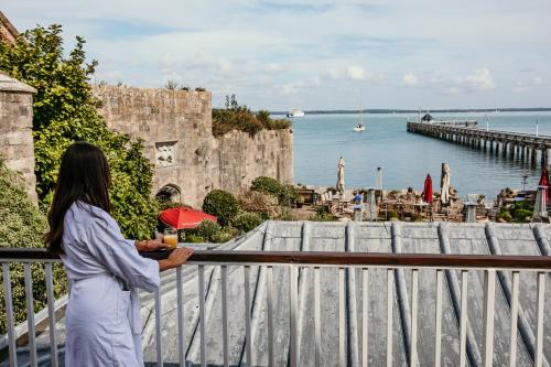 a woman standing on a balcony looking at the water at The George Hotel and Beach Club in Yarmouth