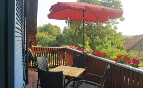 a table and chairs with a red umbrella on a deck at Ferienwohnung am Sternhagener See in Lindenhagen