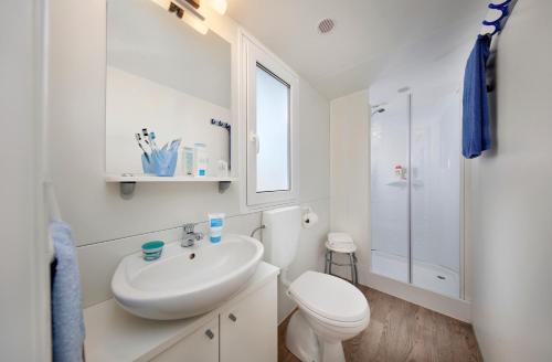 a white bathroom with a toilet and a sink at Albatross Mobile Homes on Camping Cisano & San Vito S. p. A. in Bardolino