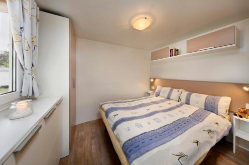 a small bedroom with a bed and a window at Albatross Mobile Homes on Camping Cisano & San Vito S. p. A. in Bardolino