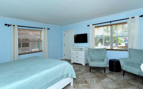 een slaapkamer met een bed, een stoel en een televisie bij Coriander Cottage in Siesta Key
