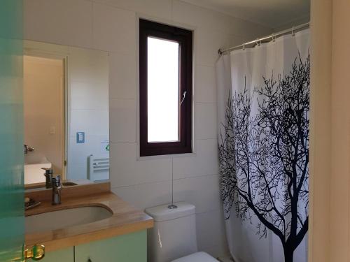 a bathroom with a toilet and a shower curtain with a tree on it at Tiny Apartment Las Puyas Ocean View in Boca Pupuya