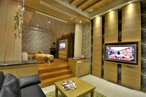 a living room with a tv and a bedroom at Hea Duenn Motel in Taichung