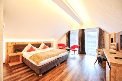 a bedroom with a bed and a desk and windows at Hotel Ferienglück in Ischgl