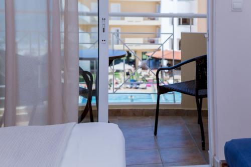 a bedroom with a bed and a view of a balcony at Sunny Bay Hotel in Kissamos