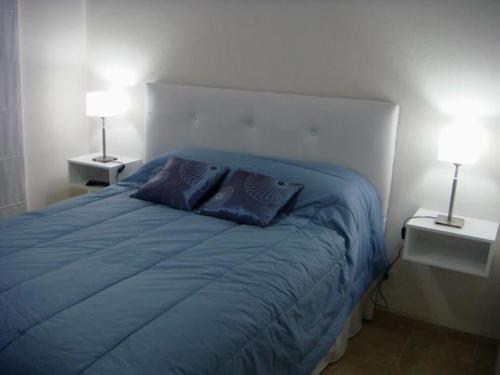 1 dormitorio con 1 cama azul y 2 almohadas en Pinamar Alquilo Frente Al Mar en Ostende