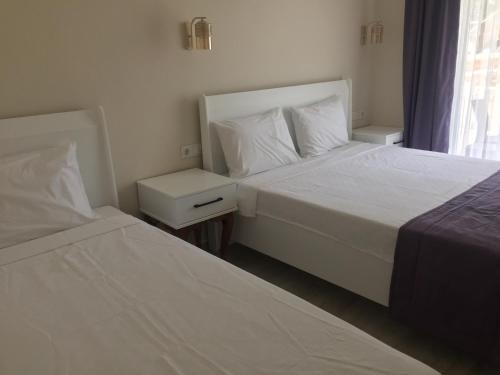 two beds in a hotel room with white sheets at Vespera hotel in Dalyan