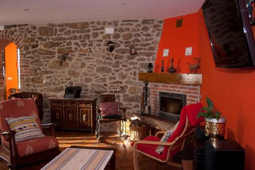 a living room with a stone fireplace and red walls at Casa La Escuela in Tuilla
