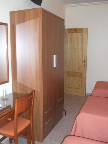 a bedroom with two beds and a desk and a wooden cabinet at Hostal Casa Juan in Lorca
