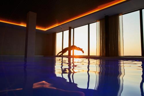 a person standing in a swimming pool in a room at Hotel de Blanke Top in Cadzand-Bad