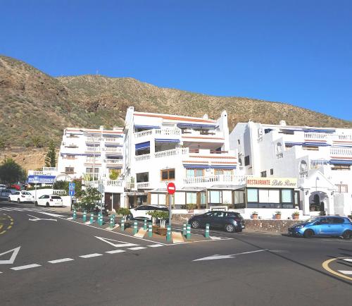 un grande edificio bianco con le auto parcheggiate di fronte di Ocean Dreams Suite heated pool a Los Cristianos