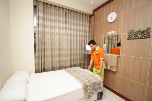 un hombre en una habitación con una cama y un espejo en The Cabin Hotel, en Yogyakarta