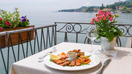 a plate of food on a table with a view of the water at Hotel Du Lac in Gargnano