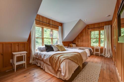 a bedroom with two beds and two windows at Chic log chalet with hot tub - Mont-Tremblant north side by Reserver.ca in Lac-Superieur
