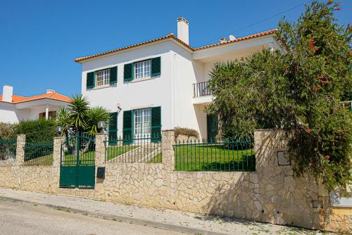 a white house with a stone wall and a fence at Villa Terra Da Eira in Mafra