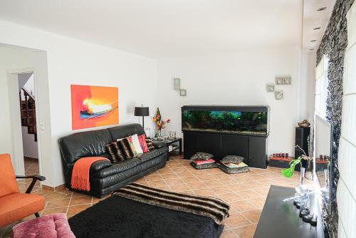 a living room with a black leather couch and a fish tank at Villa Terra Da Eira in Mafra