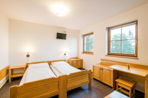 a room with two beds and a desk and window at Horský Hotel Kohútka in Nový Hrozenkov