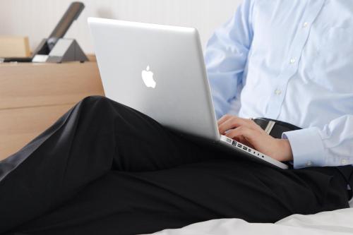 a person sitting on a bed using a laptop computer at Hiroshima Tokyu REI Hotel in Hiroshima