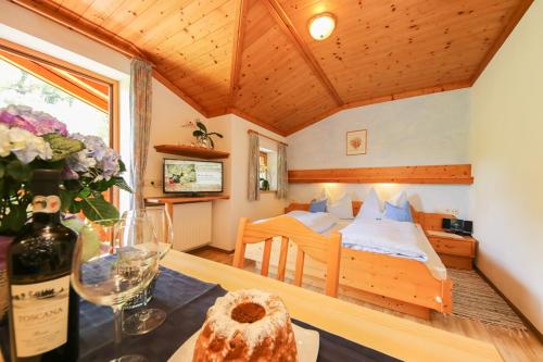 ein Schlafzimmer mit einem Bett und einem Tisch mit einer Flasche Wein in der Unterkunft Haus Breithornblick in Maria Alm am Steinernen Meer