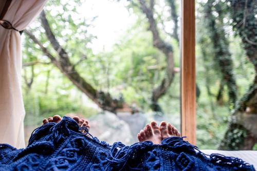 a person laying on a bed looking out a window at Duende Hotel in Lagodekhi