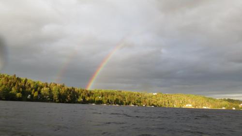 a rainbow in the sky over a body of water at Le Gite de la Renarde in Saint-Félix-d'Otis
