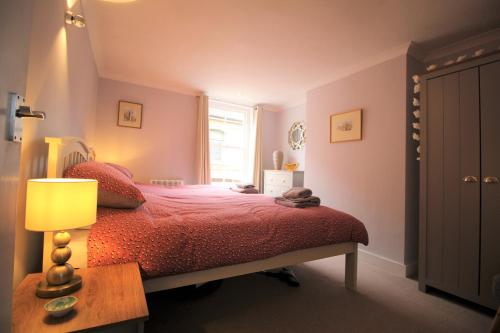 a bedroom with a bed with a red comforter and a window at 1 Steam Packet Cottage in Canterbury