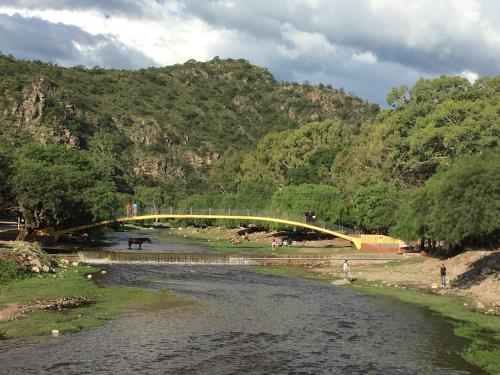 eine Brücke über einen Fluss neben einem Berg in der Unterkunft Lo de Jenny in San Marcos Sierras