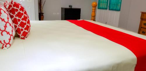 a white bed with red and white pillows on it at Casa Tamar Guest Apartment in Kingston
