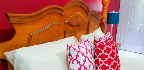a bed with a wooden head board and two pillows at Casa Tamar Guest Apartment in Kingston