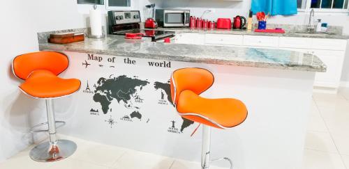 a kitchen with two orange chairs and a map of the world at Casa Tamar Guest Apartment in Kingston