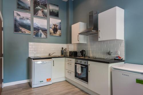 a kitchen with white appliances and pictures on the wall at Wellington Park Boutique Apartments in Belfast
