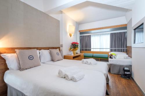 two beds in a hotel room with towels on them at TH Marilleva in Mezzana