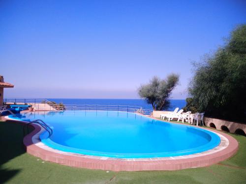 uma grande piscina com o oceano ao fundo em Iris house em Agnone Bagni