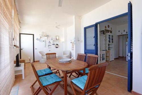 uma sala de jantar com uma mesa de madeira e cadeiras em Balcone Sul Mediterraneo em Punta Secca