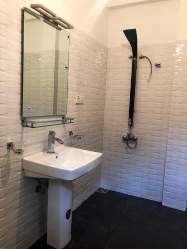 a white bathroom with a sink and a mirror at Gimhana Guest House in Nuwara Eliya