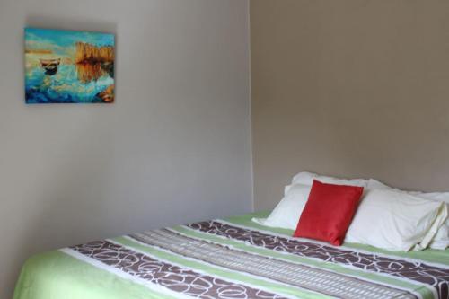 ein Schlafzimmer mit einem Bett mit einem roten Kissen in der Unterkunft Casa Canukatan in Chelem