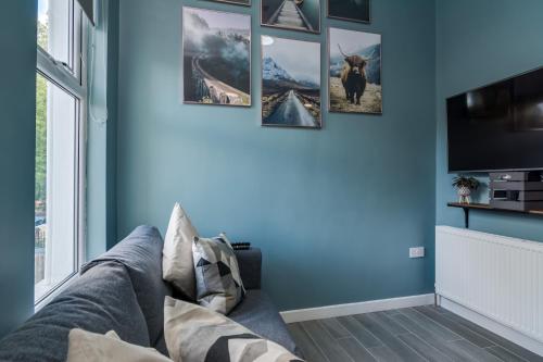 a living room with blue walls and a gray couch at Wellington Park Boutique Apartments in Belfast
