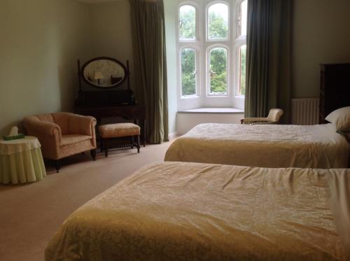 a bedroom with two beds and a chair and a window at Greenham Hall in Wellington