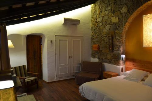 a bedroom with a bed and a stone wall at Hotel Galena Mas Comangau in Begur