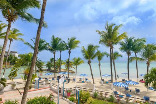 una playa con palmeras y el océano en Canella Beach Hotel en Le Gosier