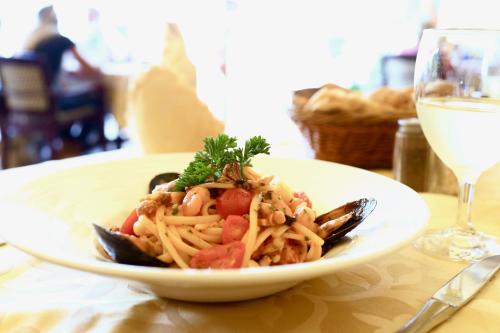 a plate of pasta on a table with a glass of wine at Hotel Victoria in Lugano